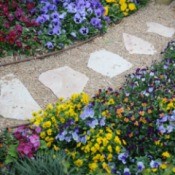 Gravel garden path with colorful flowers on each side.