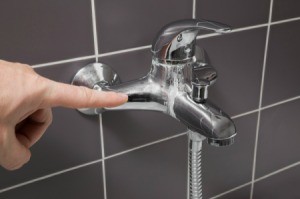 Hand pointing to calcium deposits on a faucet.