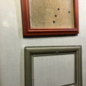 A broken picture frame underneath another frame that has had the glass replaced.