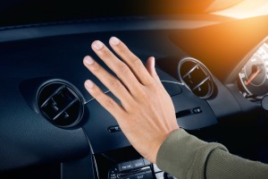 Hand feeling the air coming out of a car vent.