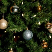 Close up of Christmas tree with lights and gold and silver baubles.