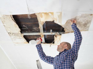 Man repairing ceiling that has a hole