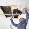 Man repairing ceiling that has a hole