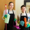 Two women with cleaning supplies in an apartment