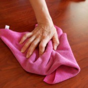 Hand using cloth towel to clean a wooden table