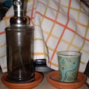 A soap dispenser and a water glass inside terra cotta planter bases.