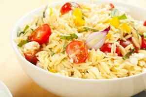 Orzo in a bowl with tomatoes and shallots.