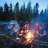 Family out camping siting around fire at dusk