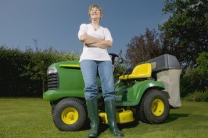 Woman standing next to a riding lawn mower.