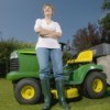 Woman standing next to a riding lawn mower.