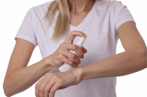 Woman spraying her arm with insect repellent.