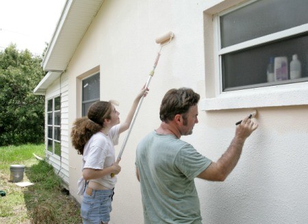 Father and daughter painting the exterior of their house.