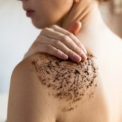 Woman Exfoliating her shoulder with coffee grounds