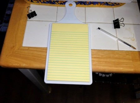 A small legal pad that will be attached to a small cutting board with binder clips.