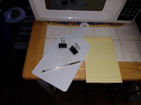 A small legal pad that will be attached to a small cutting board with binder clips.