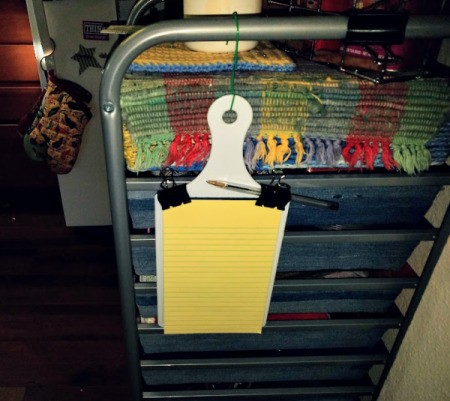 A small legal pad attached to a small cutting board with binder clips.