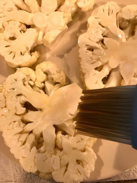 Brushing Cauliflower with oil and herbs