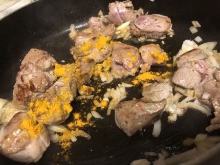 adding turmeric to meat and onions