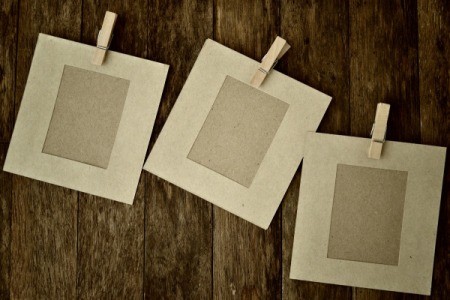 Paper picture frames with clothes pins on wood background.