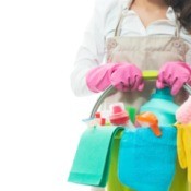 Woman holding a bucket full of cleaning supplies.