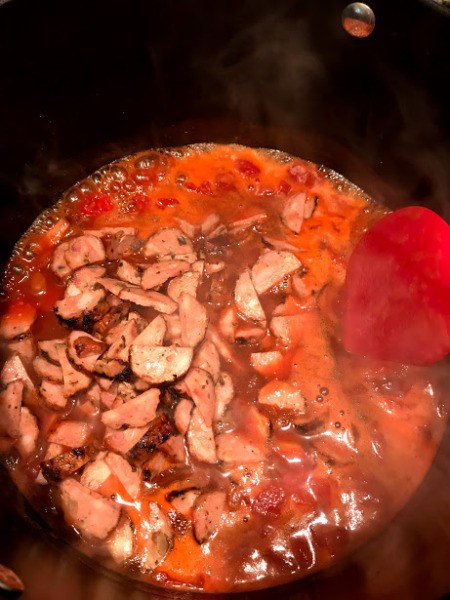 adding sausage to beans and tomatoes