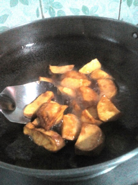 Sugar added to sweet potatoes in pan