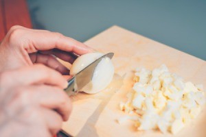 Hard boiled eggs being chopped into small pieces.
