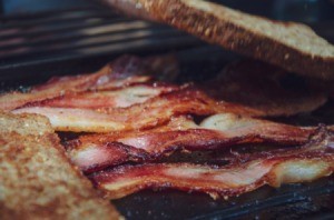 Bacon being cooked with slices of bread soaking up the grease.