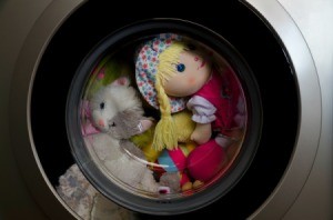 Doll and stuffed animals in a washing machine.