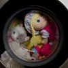 Doll and stuffed animals in a washing machine.