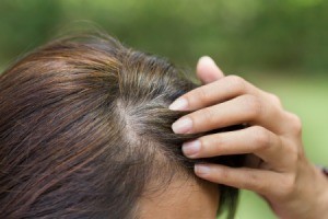 Young woman shows her gray hair roots.