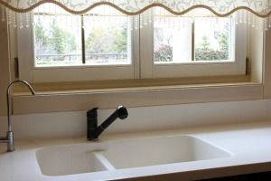 Corian kitchen sink with a window behind.