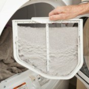 Hand pulling lint trap out of dryer.