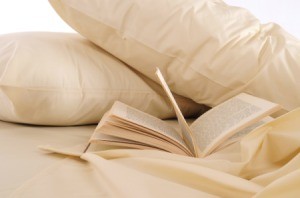 Beige pillow cases on a bed with an open book.