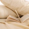 Beige pillow cases on a bed with an open book.