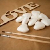Styrofoam hearts with a wooden cutout of the word "love" and some paintbrushes.