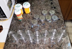 A row of small empty mason jars with prescription medication bottles.