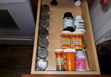 A row of mini mason jars in a drawer with medication for each day inside, with the first one flipped over to denote that it is empty.