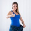 Woman wearing old pair of extra large jeans giving thumbs up