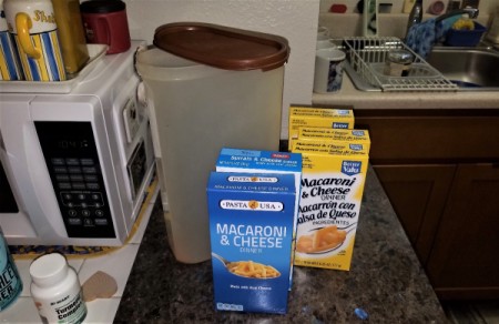 Boxes of macaroni and cheese next to a large empty container.