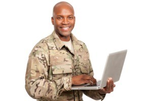 Soldier smiles while typing on a computer.