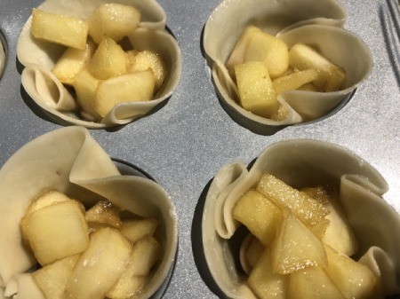 Apples added to lined muffin tins