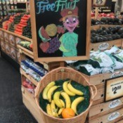 A sign at the grocery store with free fruit for kids while shopping.