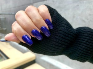 A hand with blue glittery nail polish.