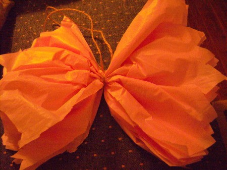 Make Big Showy Flowers from Plastic Tablecloths - orange plastic tied with a string