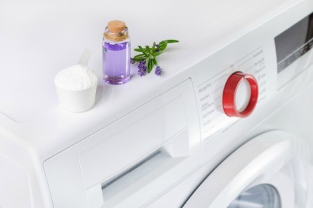 Laundry detergent and lavender on a washing machine.