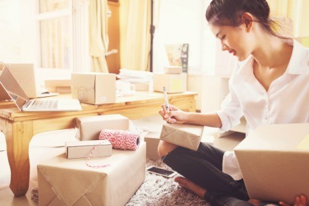 Woman surrounded by boxes, getting them ready to send.