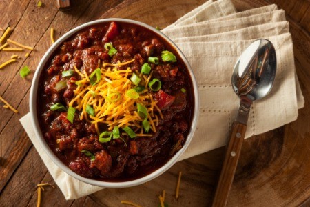 Chili with cheese and chives on wooden table