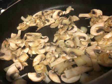 adding mushrooms to onions in pan