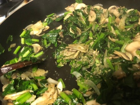 adding spinach to onions and mushrooms in pan